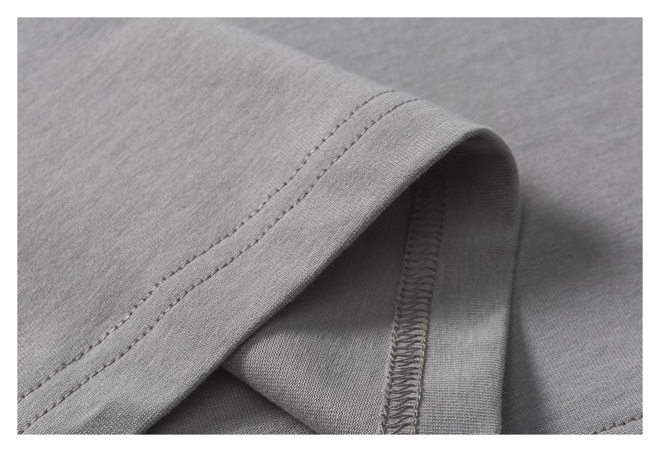 Close-up of a folded gray garment edge with double stitching and an overlocked inner seam.