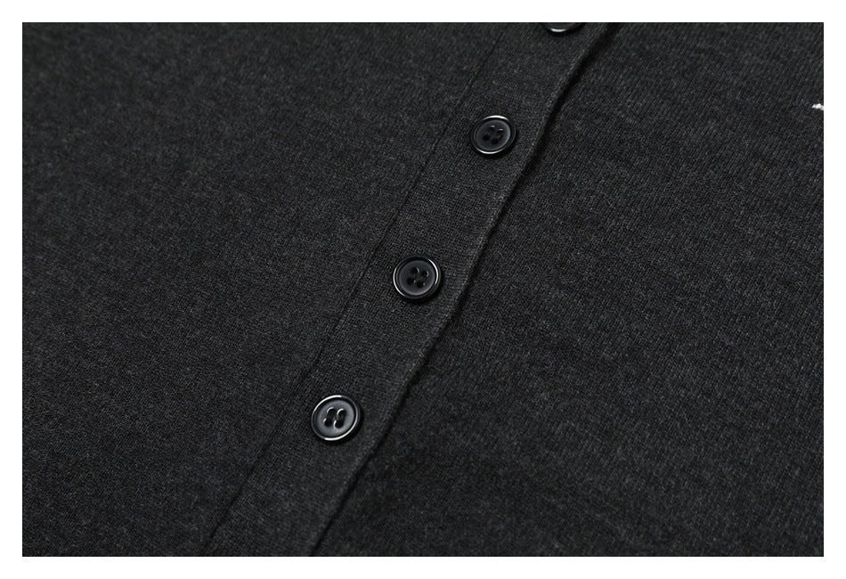 Close-up of three black buttons on the placket of a charcoal knit top.