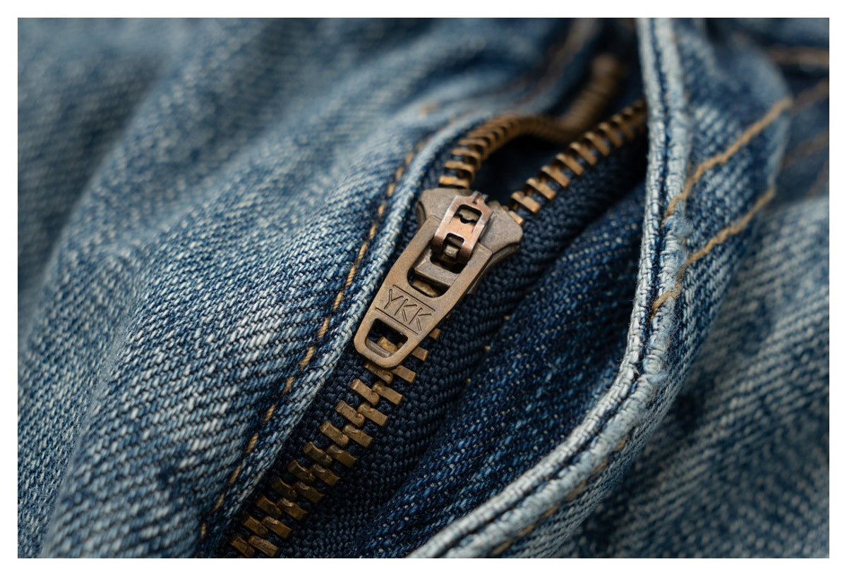 Close-up of a metal zipper and teeth on faded blue denim.