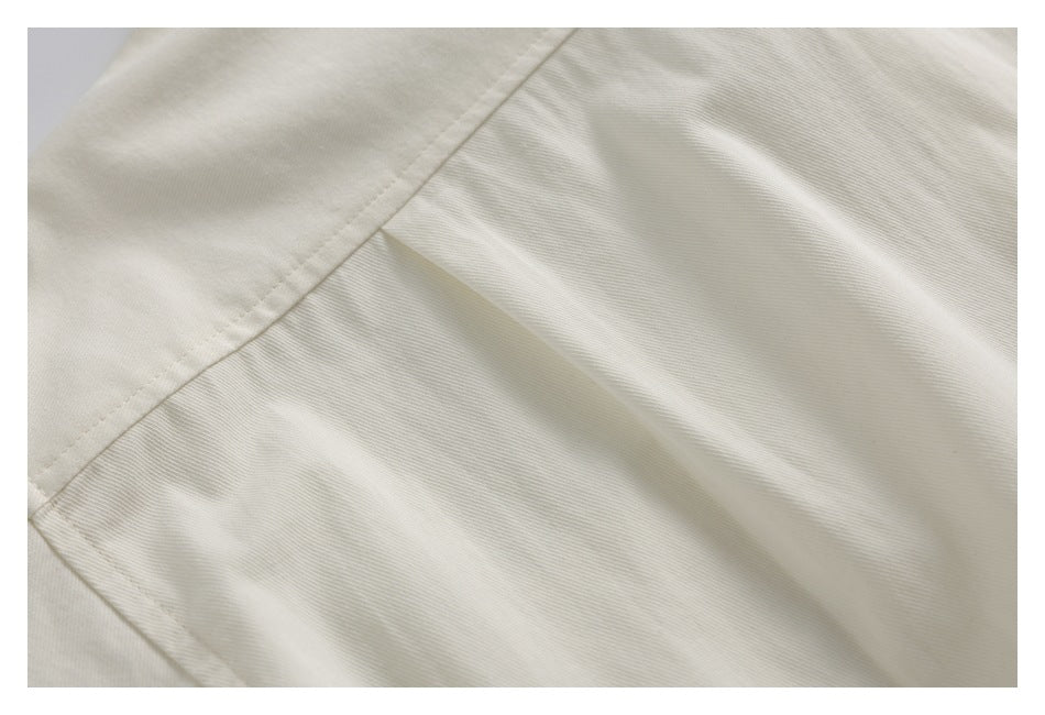 Close-up of an ivory garment seam and overlapping fabric panels.