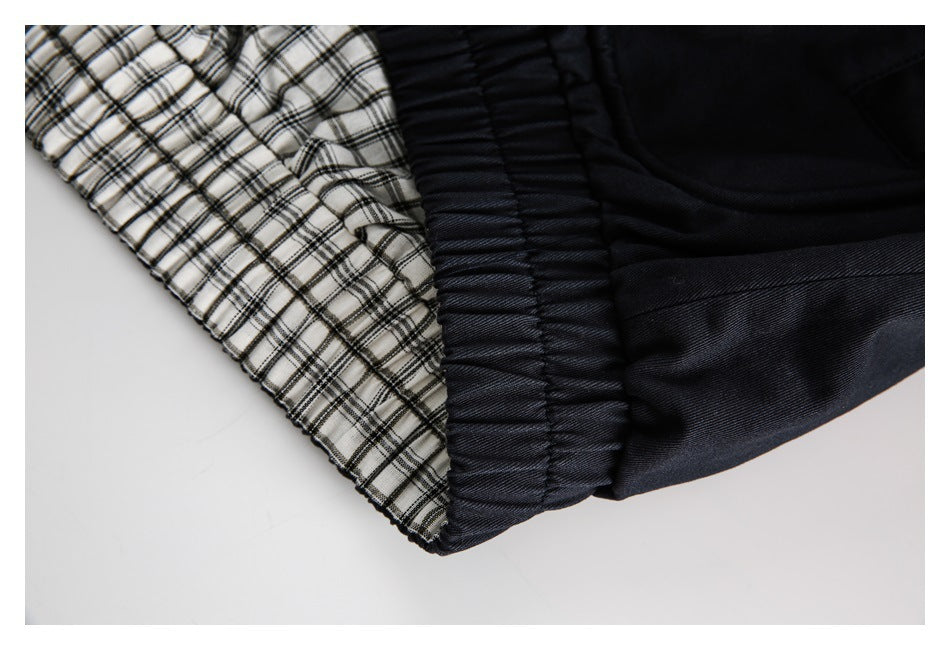 Close-up of white-and-black plaid fabric beside a black gathered elastic section.