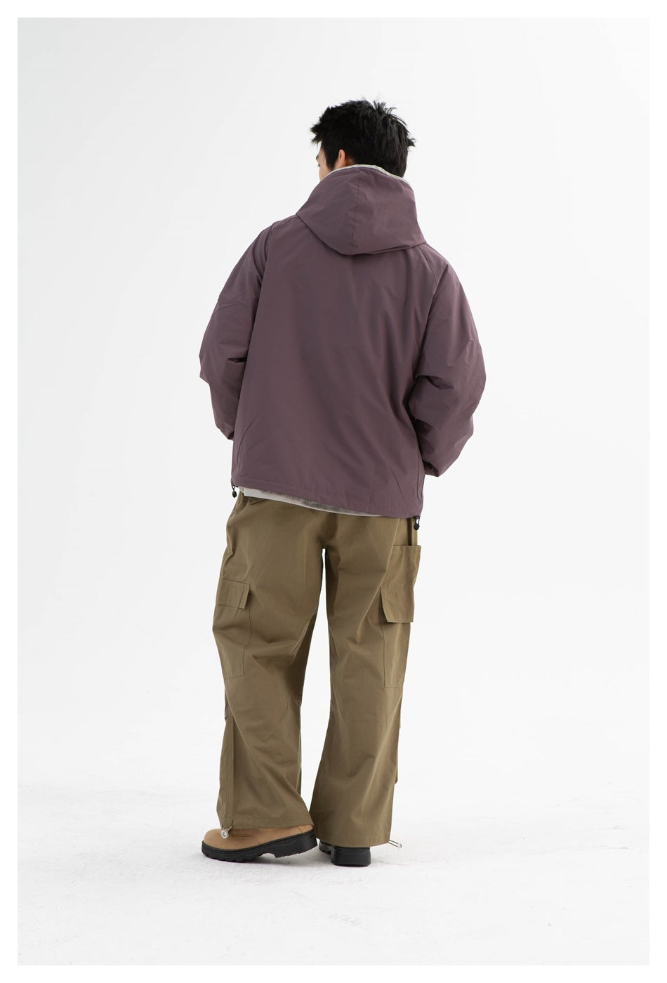 Back view of a model wearing a plum hooded jacket with olive cargo pants.