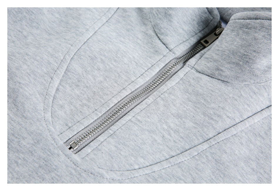 Close-up of a silver zipper and curved seam on a light gray heathered garment.