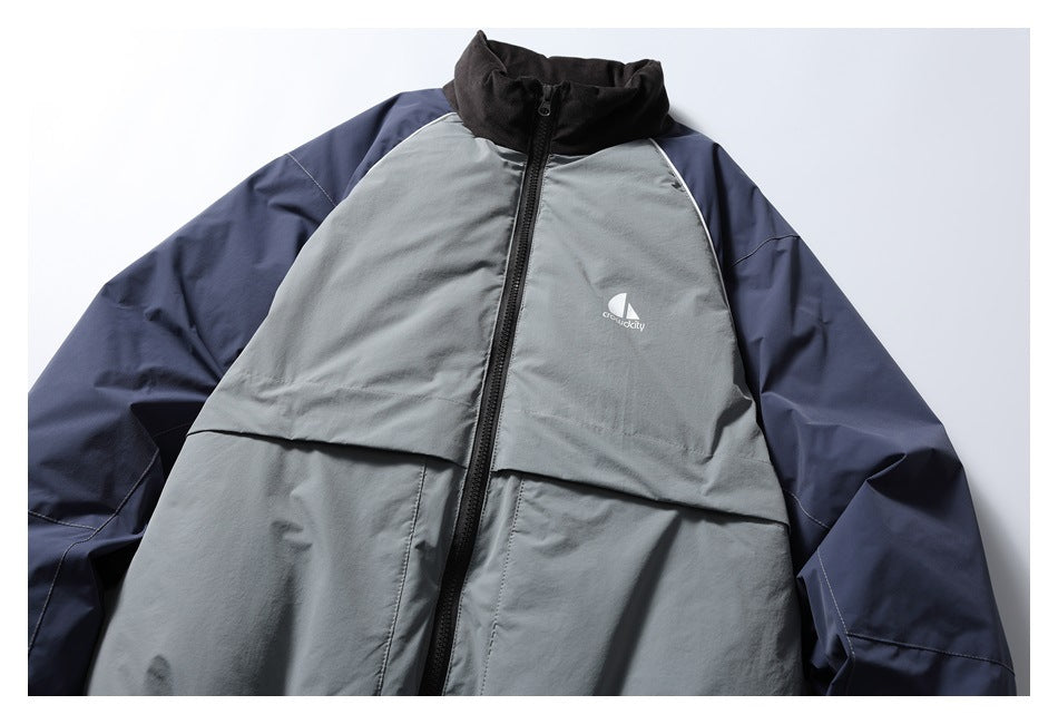 Front view of a gray and navy color-block jacket with a black stand collar, full zipper, and white chest logo.