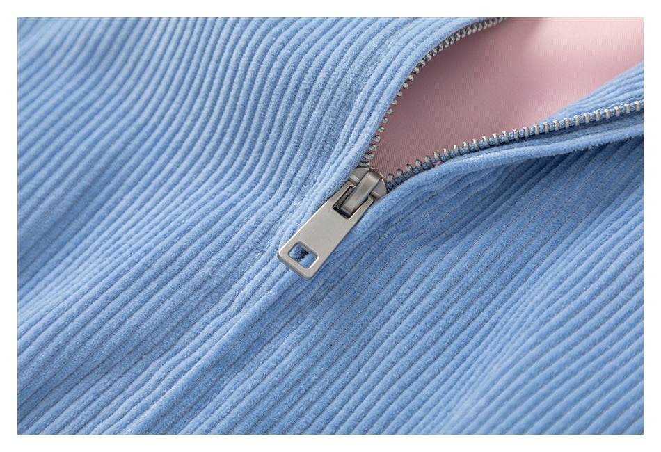 Close-up of the metal zipper and teeth on the light blue corduroy jacket, with pink lining visible.