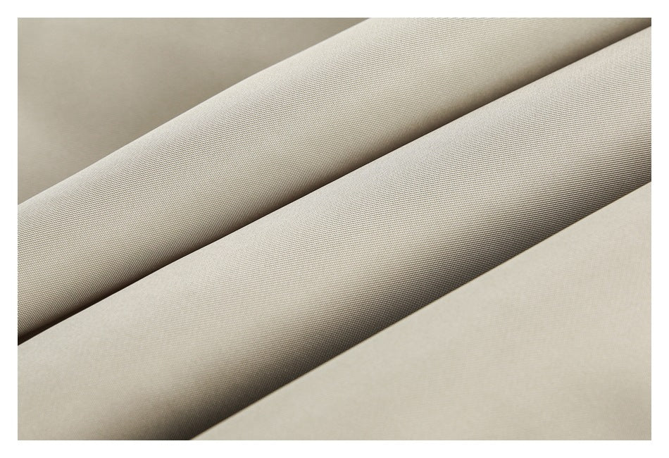 Close-up of light beige fabric arranged in folded diagonal layers, showing its fine woven texture.