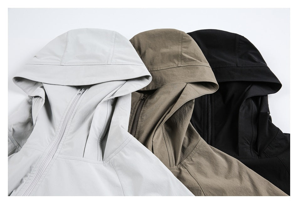 Close view of hooded jackets in light gray, taupe, and black, showing their hoods and front zippers.