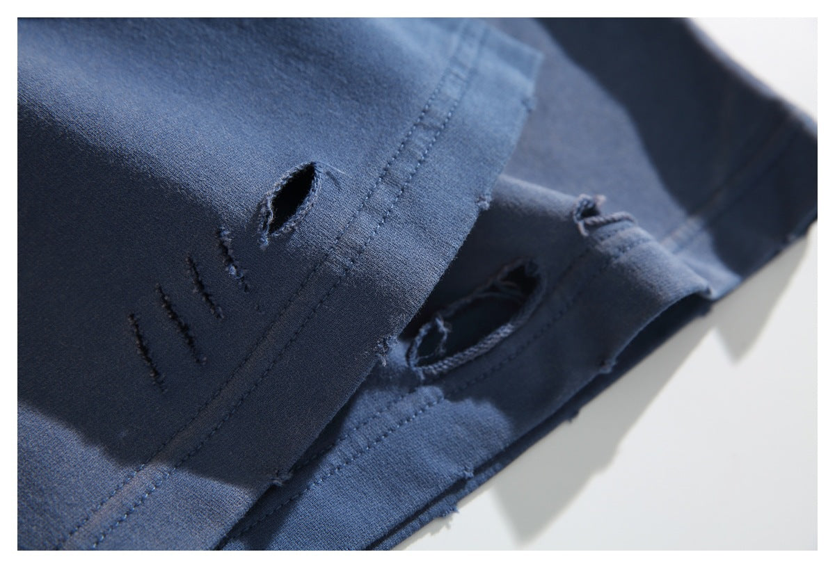 Macro view of distressed openings and stitching along a blue garment hem.