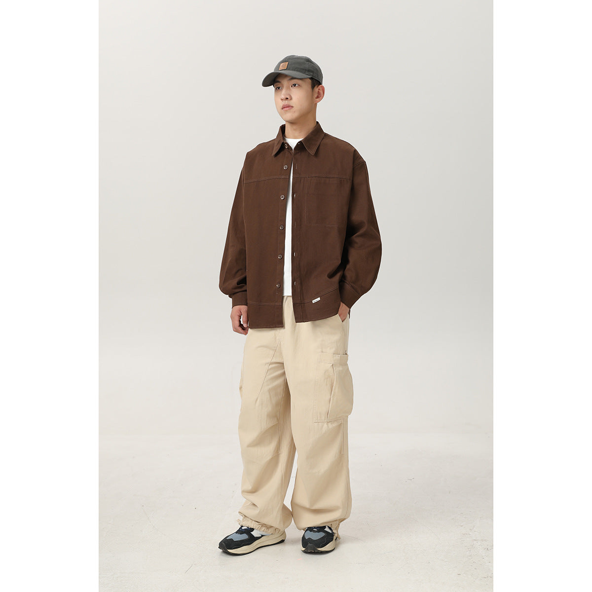 Model wearing a dark brown button-front shirt jacket with cream cargo pants, shown full length from the front.