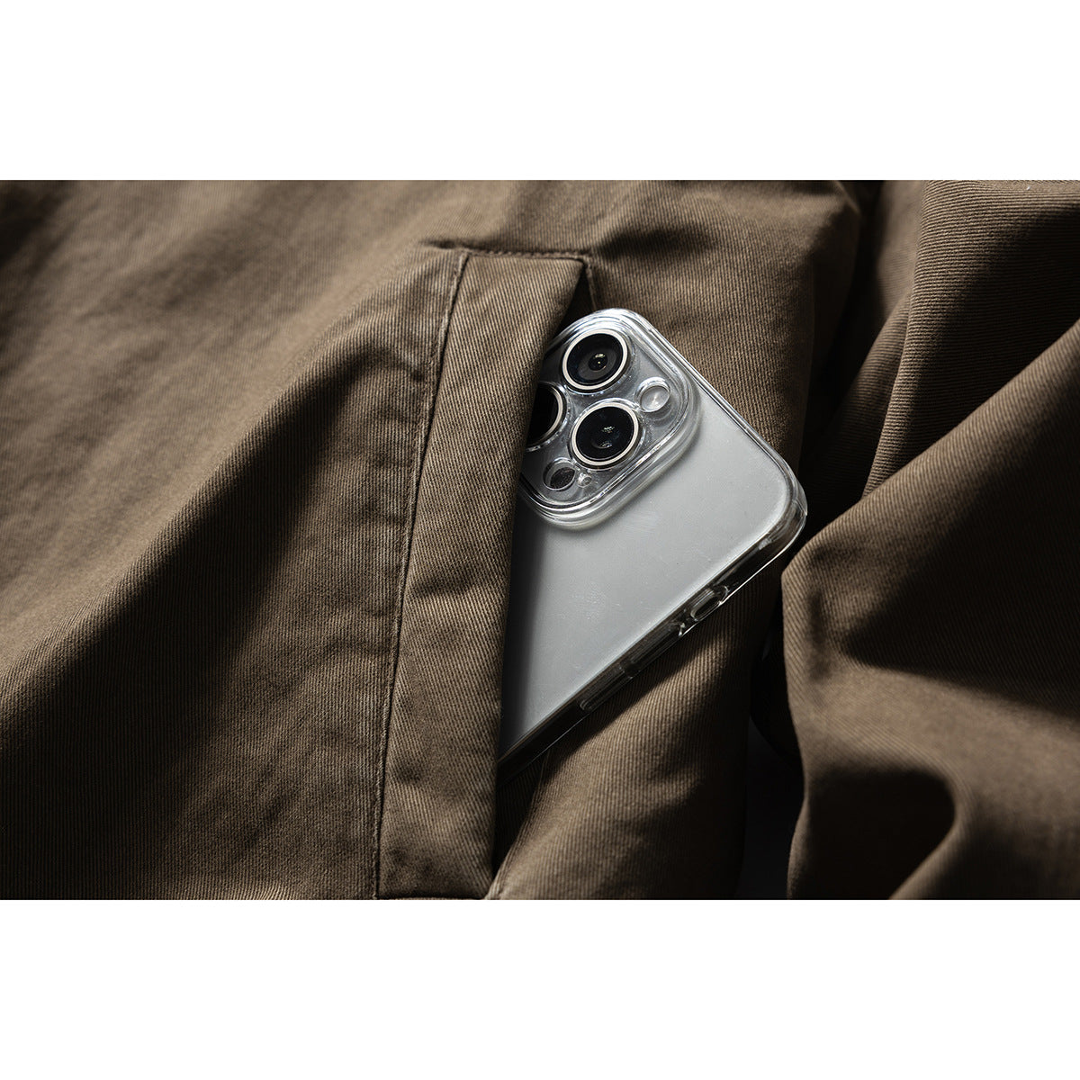 Close-up of a phone tucked into a vertical pocket on the brown jacket.