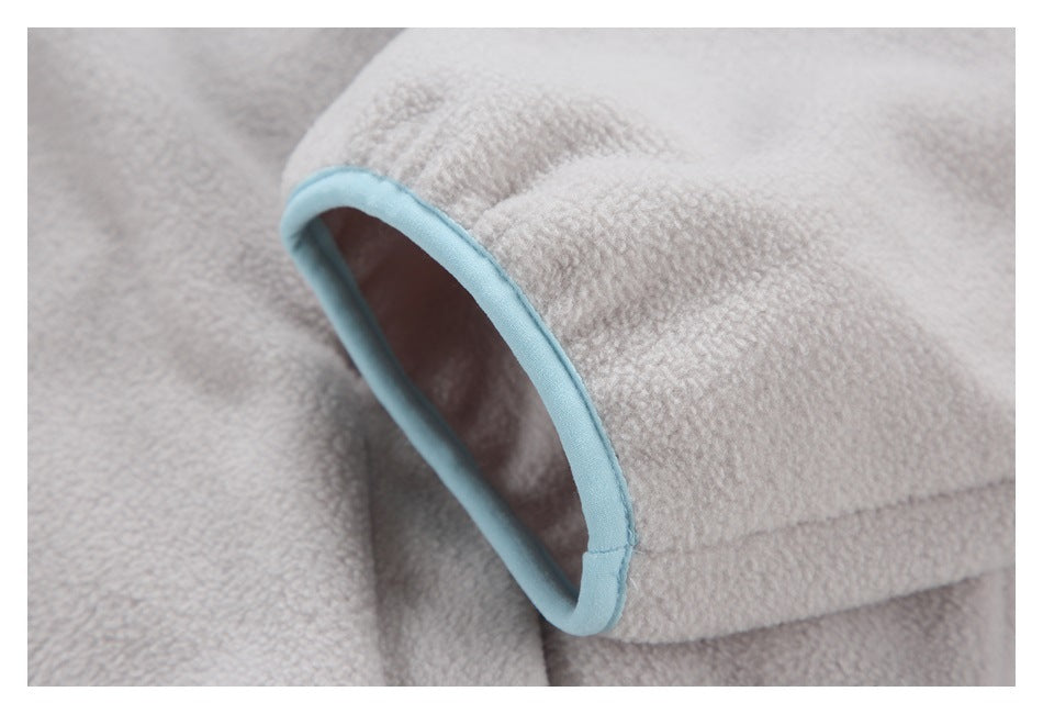 Close-up of a pale gray fuzzy garment opening edged with light blue binding.