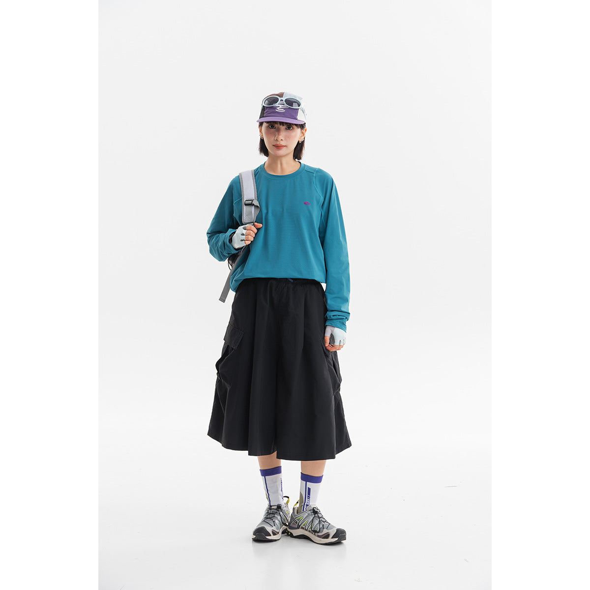 Model wearing a teal long-sleeve crewneck top and a black midi skirt.