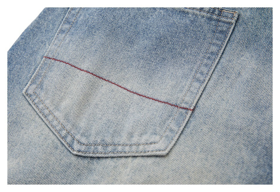 Close-up of a back pocket on faded light-blue jeans, with a red horizontal stitch accent.