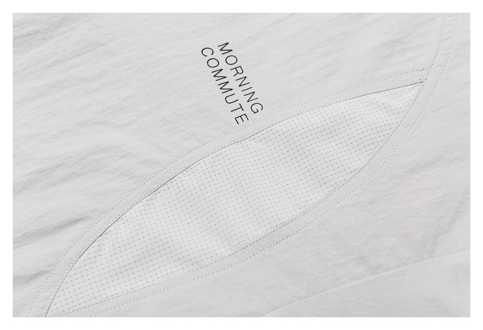 Close-up of the light gray shirt’s printed text and a curved stitched panel.