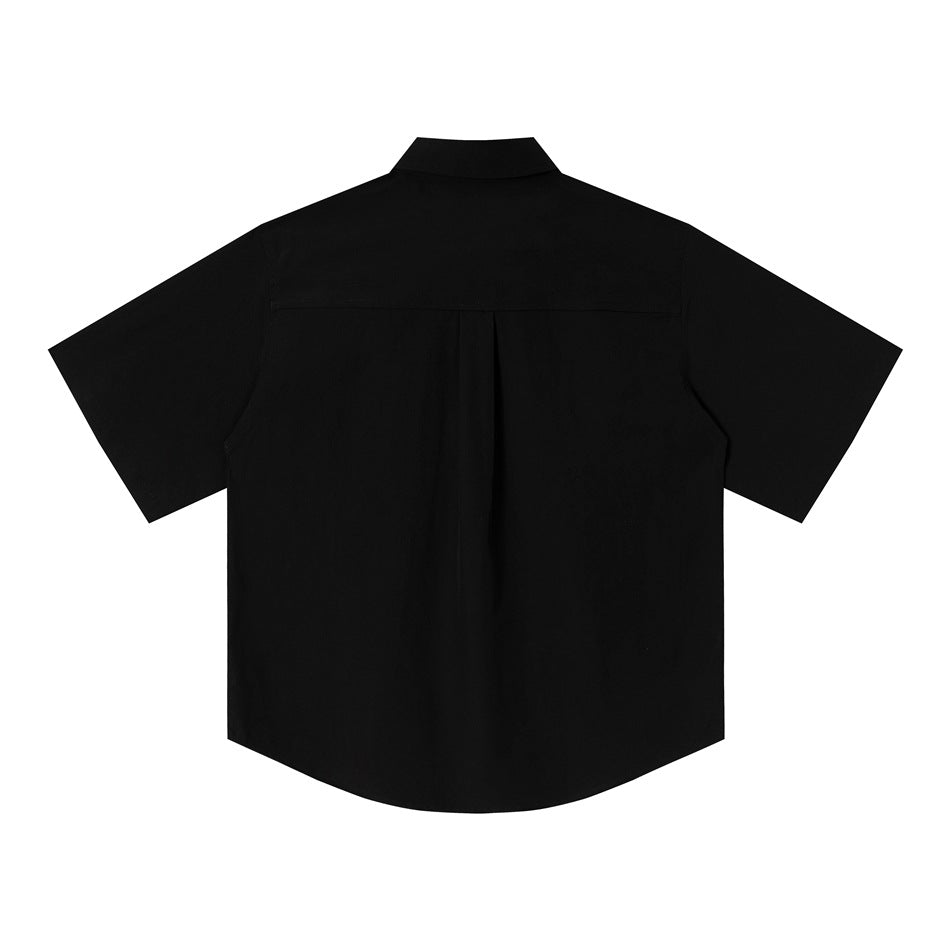 Back view of a black short-sleeve button-up shirt with a yoke and center pleat.