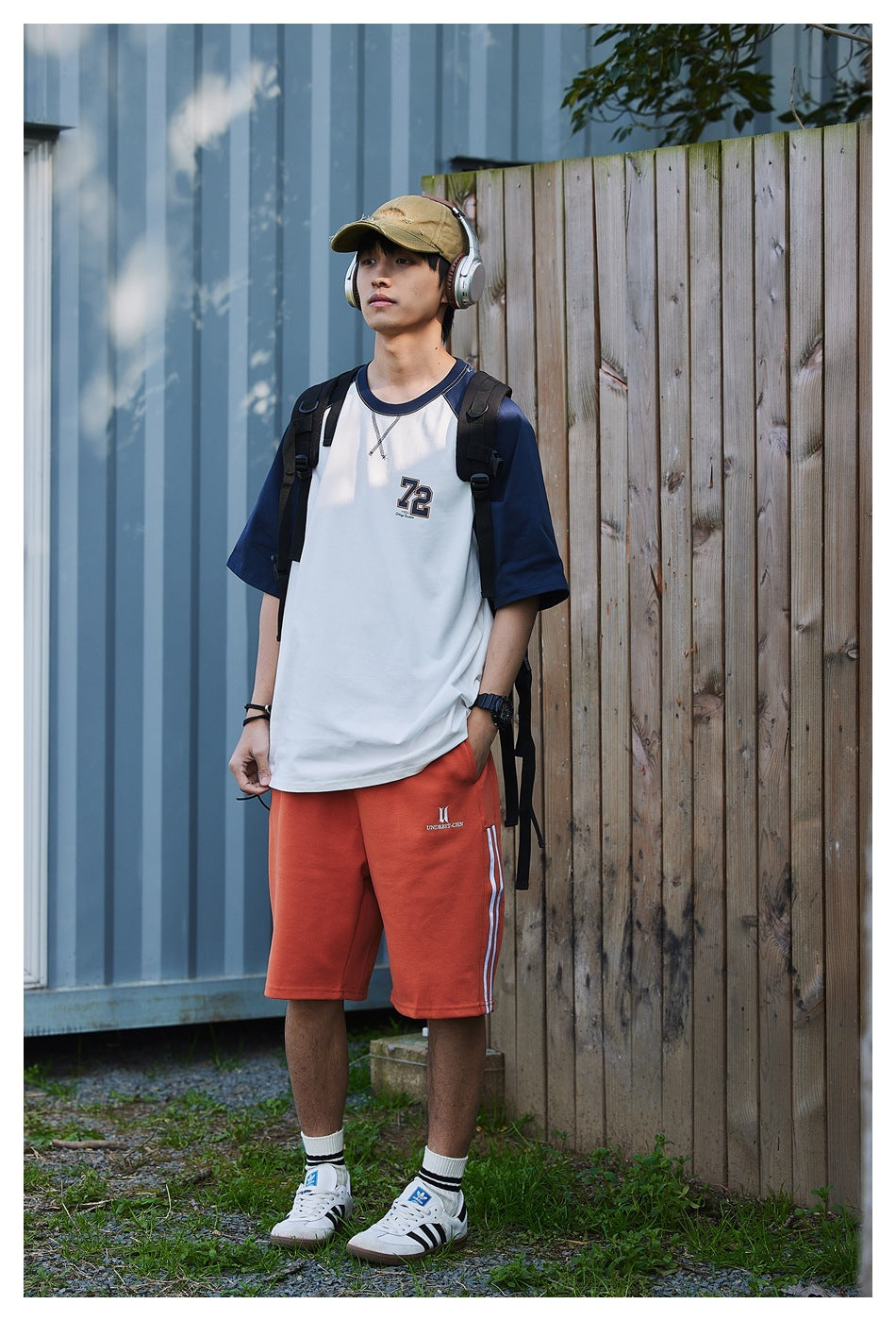 Full-length view of a model in a white and navy raglan T-shirt with a 72 chest graphic.