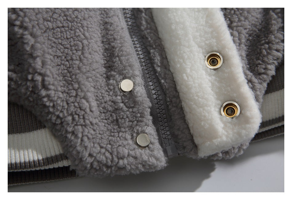 Close-up of a gray and cream fuzzy jacket's zipper, snaps, and striped ribbed hem.