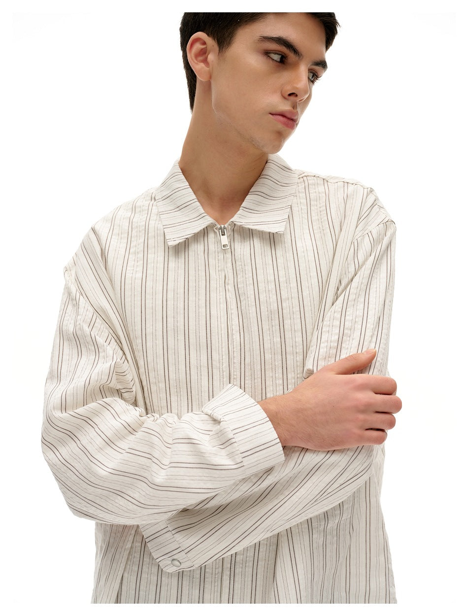 Model wearing an off-white thin-striped shirt with a wide collar, front zipper and long sleeves.