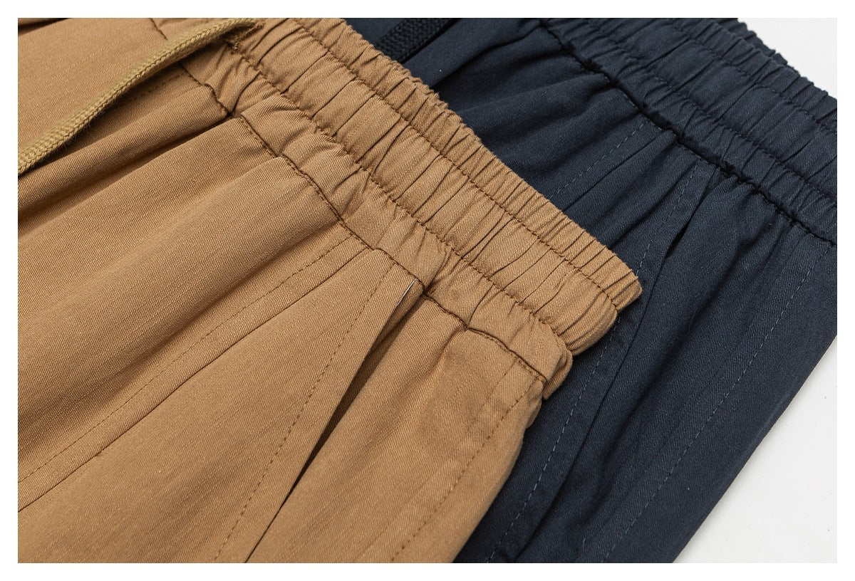 Close-up of tan and dark navy shorts showing gathered elastic waistbands and stitched panels.