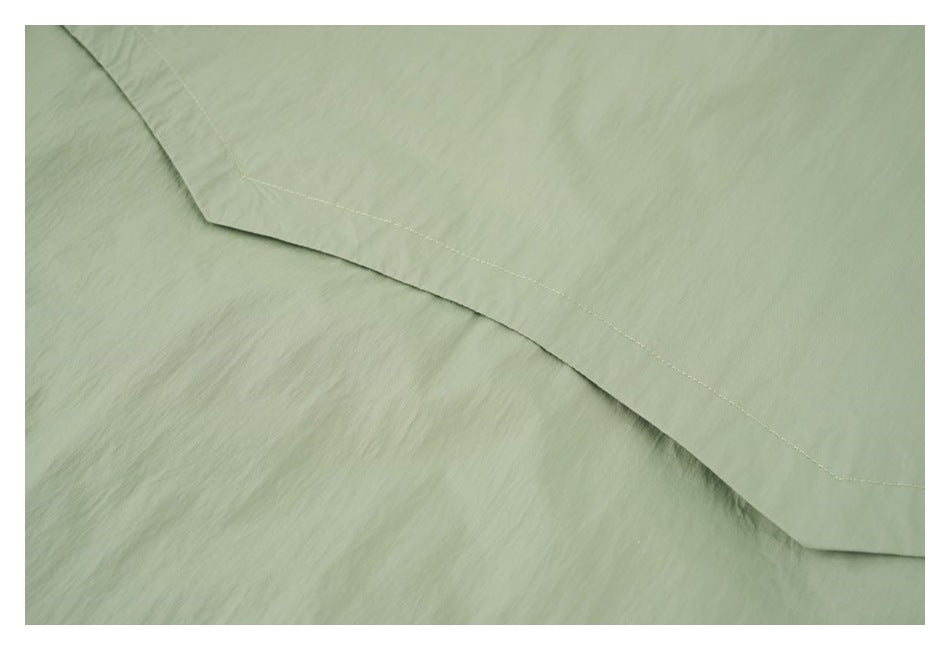 Close-up of a curved stitched seam on the sage green jacket.