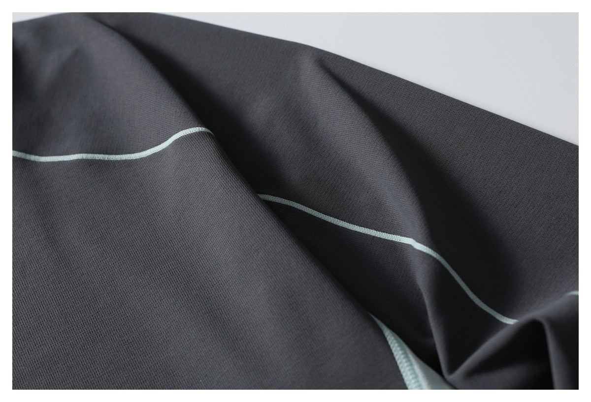 Close-up of charcoal fabric with a thin pale mint seam line.