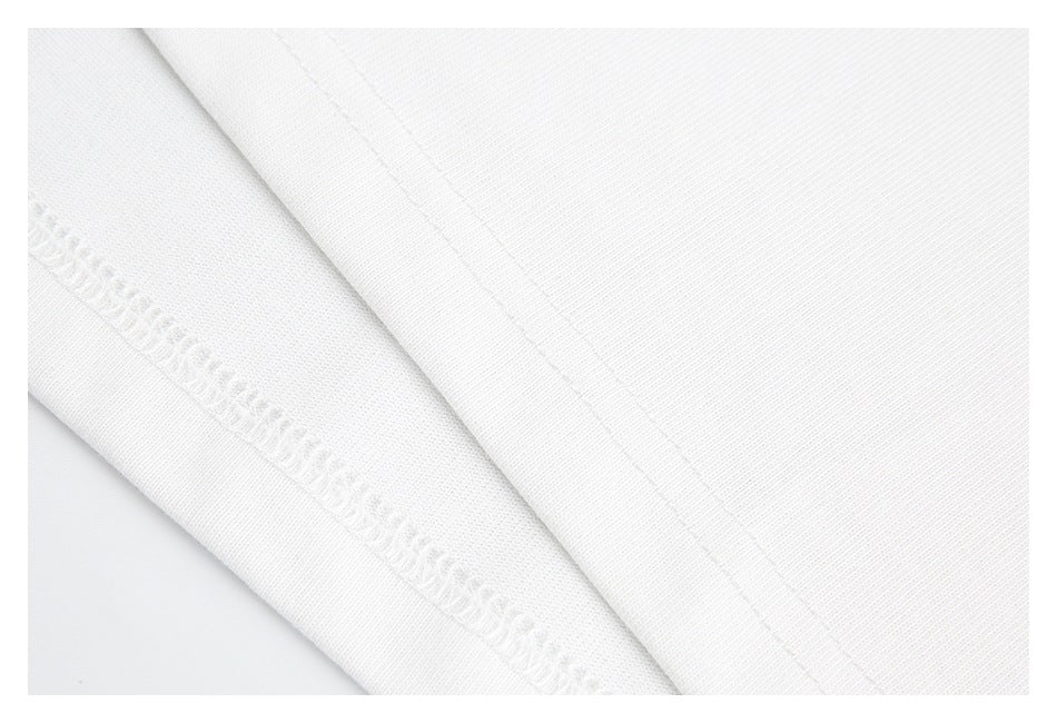 Close-up of white garment fabric with a folded edge and visible overlock stitching.