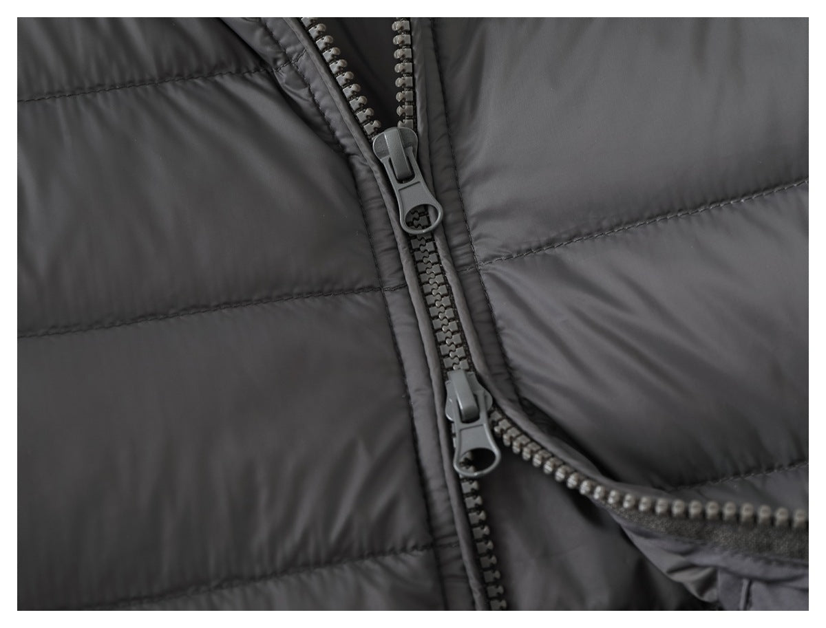 Close-up of a dark gray quilted jacket with a two-way front zipper and large pulls.