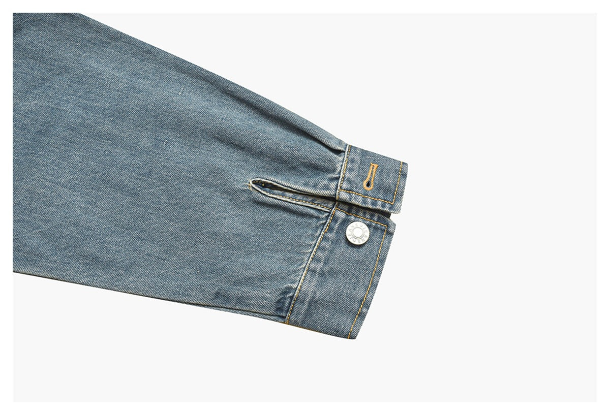 Close-up of a washed blue denim sleeve cuff with a metal button and yellow topstitching.