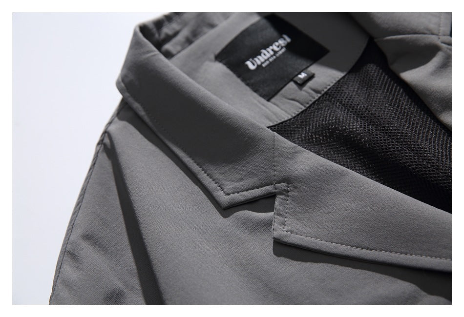 Close-up of the charcoal jacket's lapel, black mesh lining, and sewn neck label.