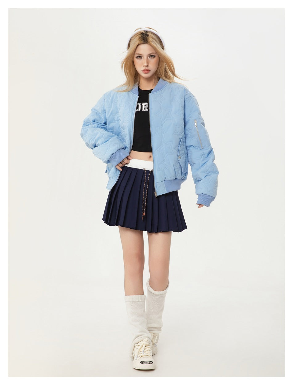 Model in the light blue star-quilted bomber jacket with a hand on hip, styled with a navy pleated skirt