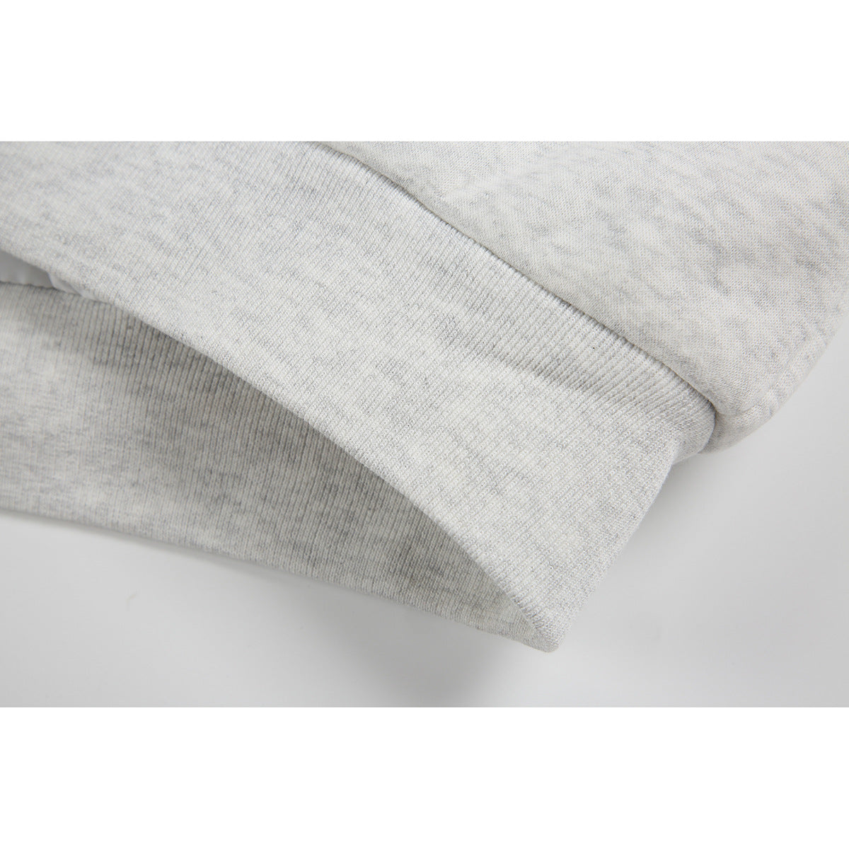 Close-up of the light gray jacket's ribbed hem and fabric.