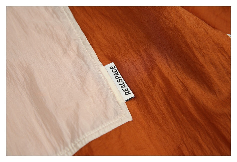 Close-up of a white REALSPACE label sewn between pale pink and rust fabric panels.