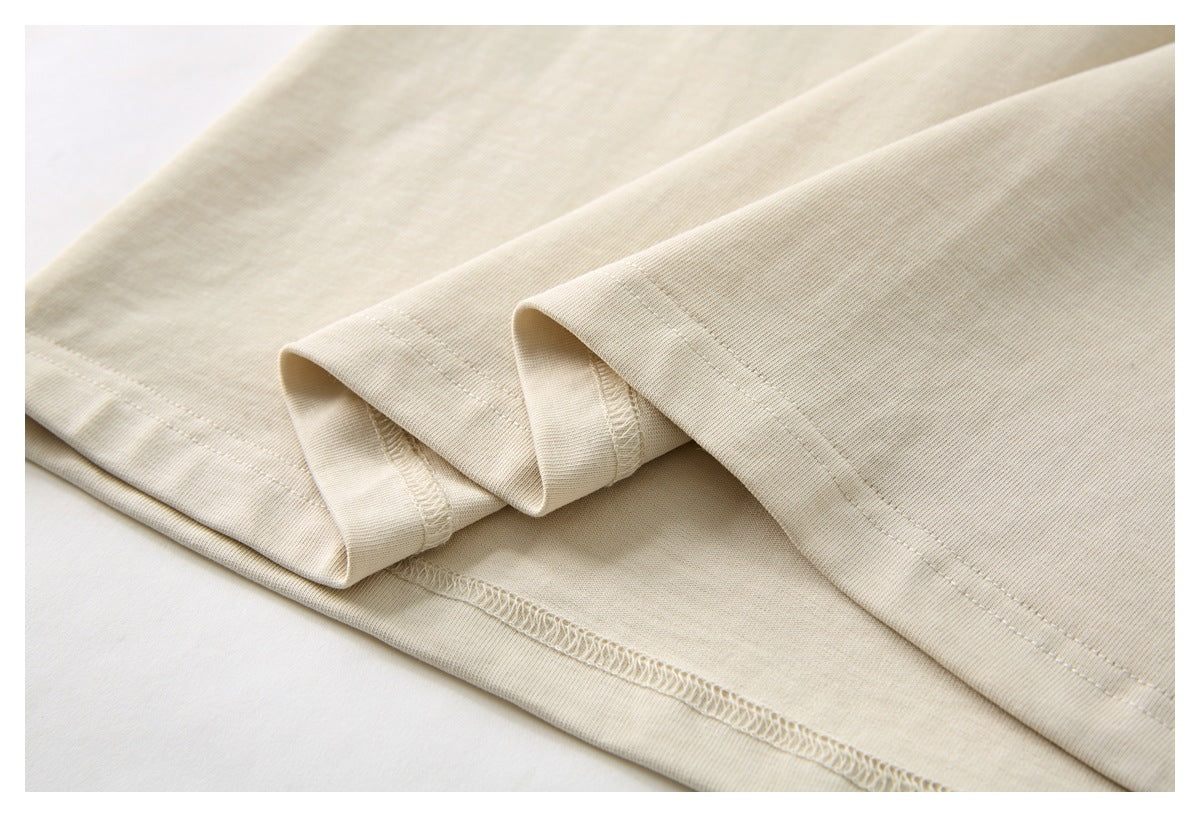 Close-up of the cream shirt's folded hem and visible overlock stitching.