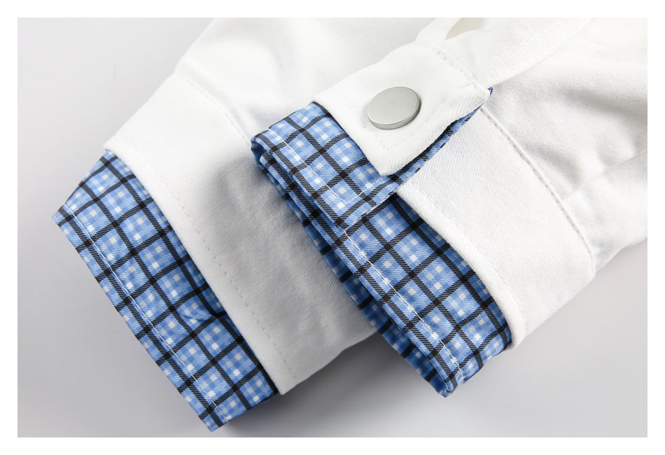 Close-up of a white garment cuff with a silver snap and blue plaid lining trim.