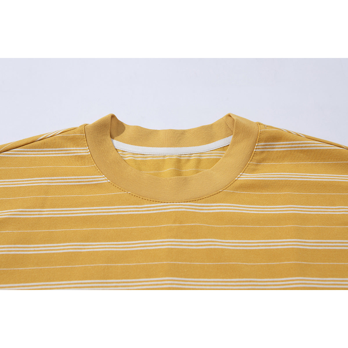 Close-up of the mustard yellow T-shirt’s ribbed crew neck and thin white horizontal stripes.