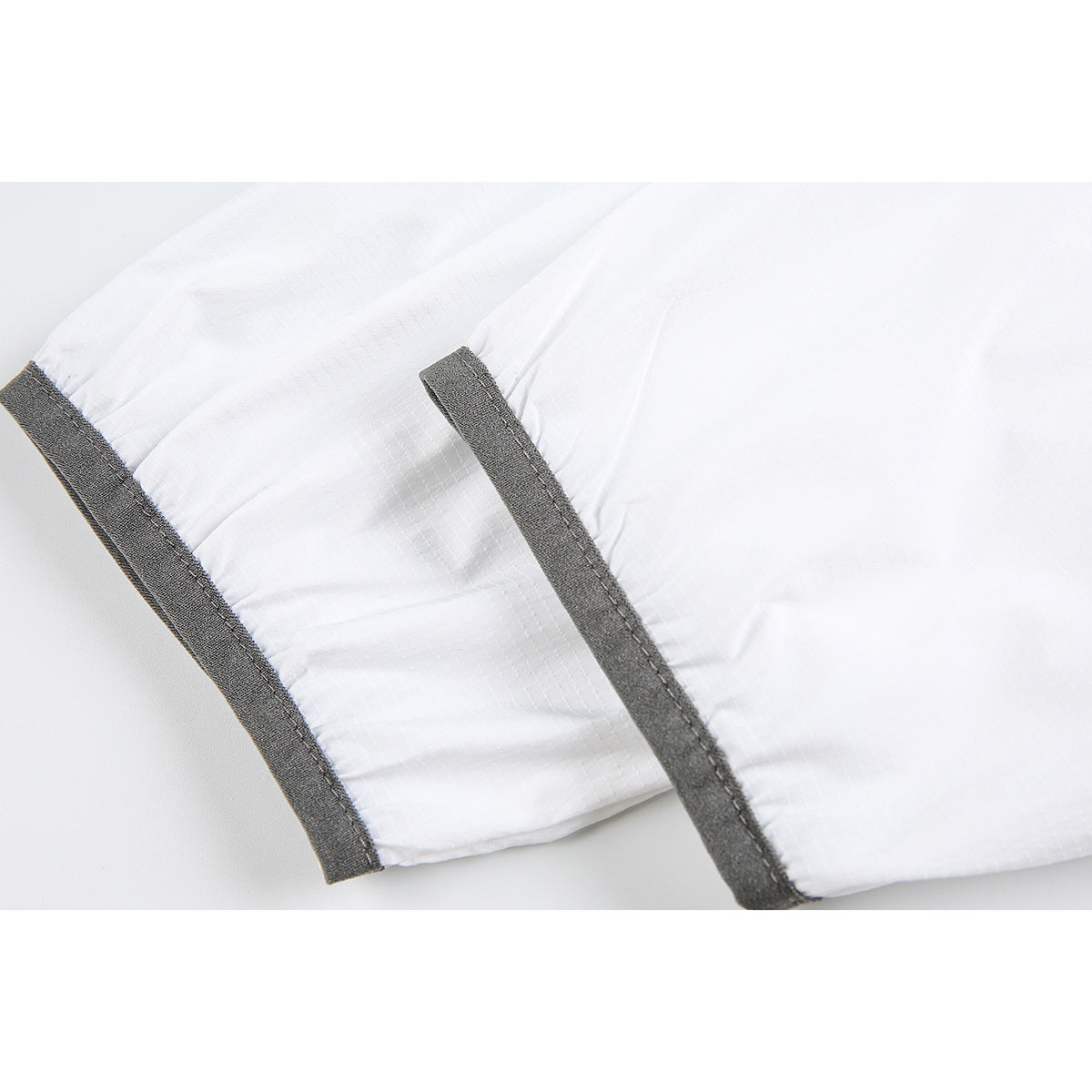 Close-up of white jacket sleeves showing gathered cuffs finished with dark gray trim.