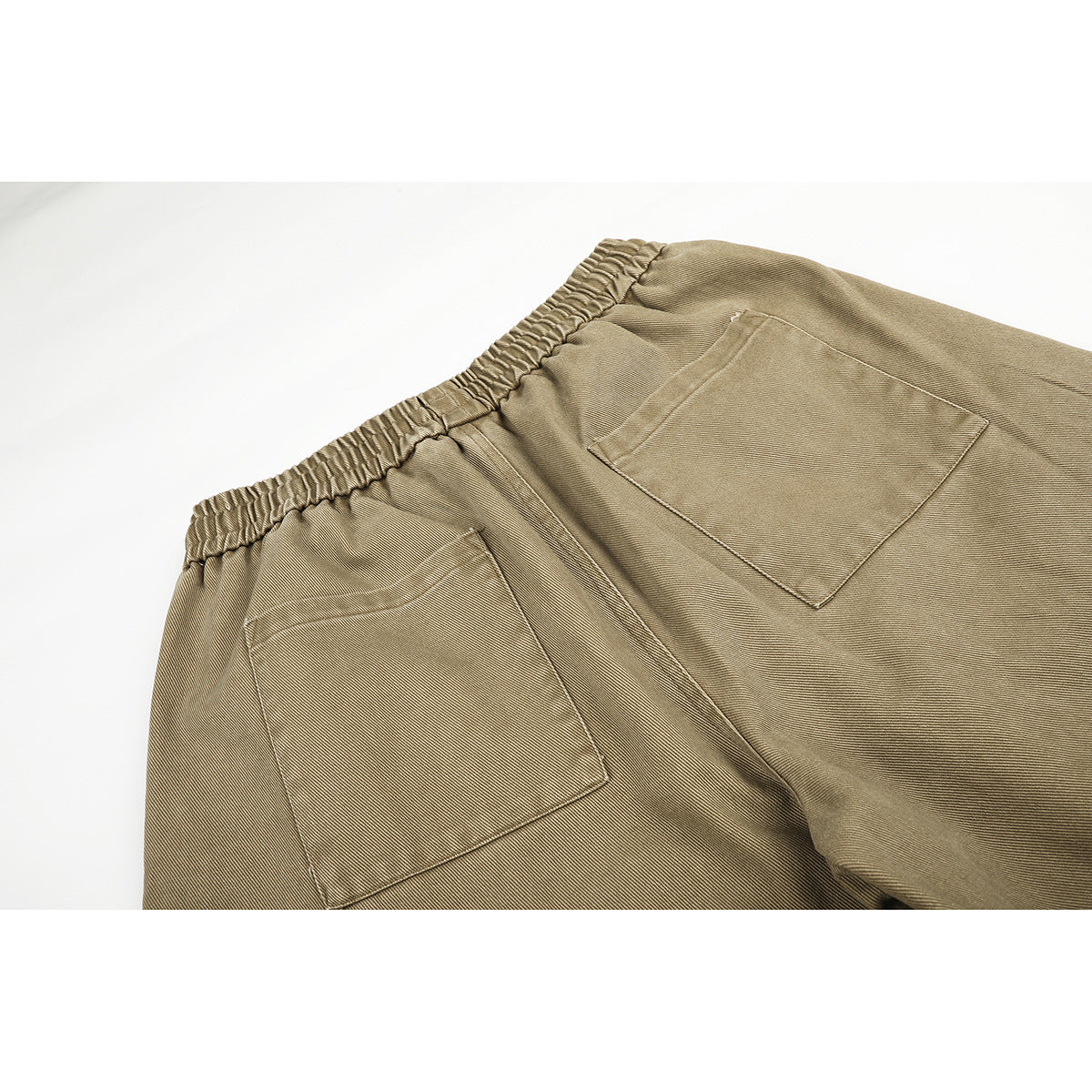 Close-up of the back of khaki pants, showing the elastic waistband and two patch pockets.