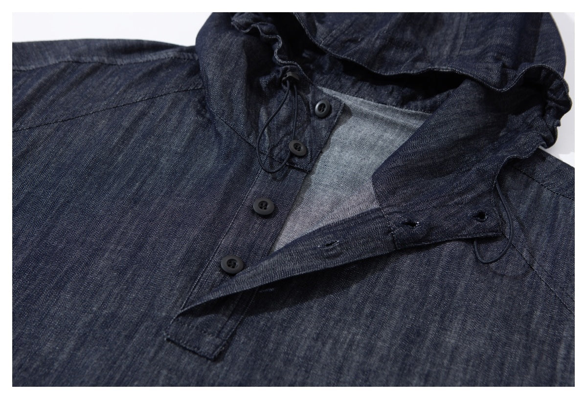 Close-up of a dark indigo jacket with its hood and front button placket partly open.