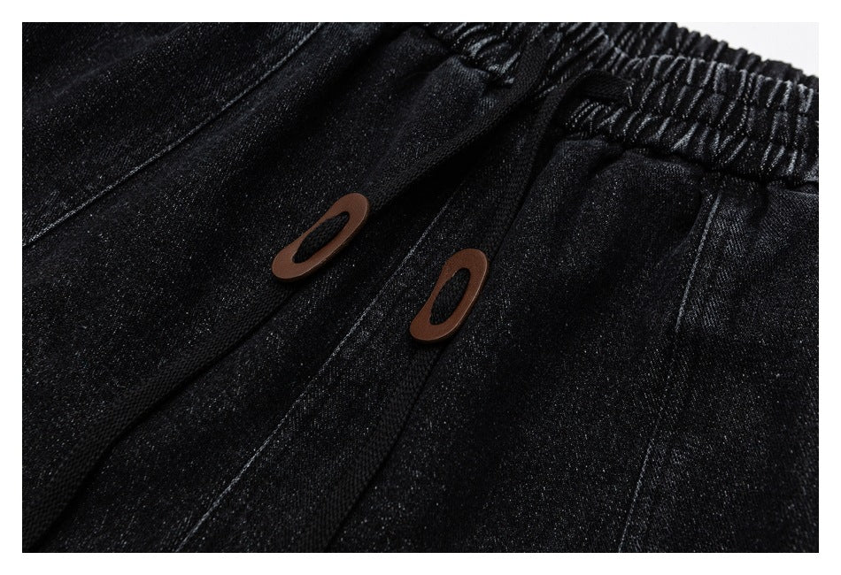 Close-up of two brown oval accents on the front of black pants below the gathered waistband.