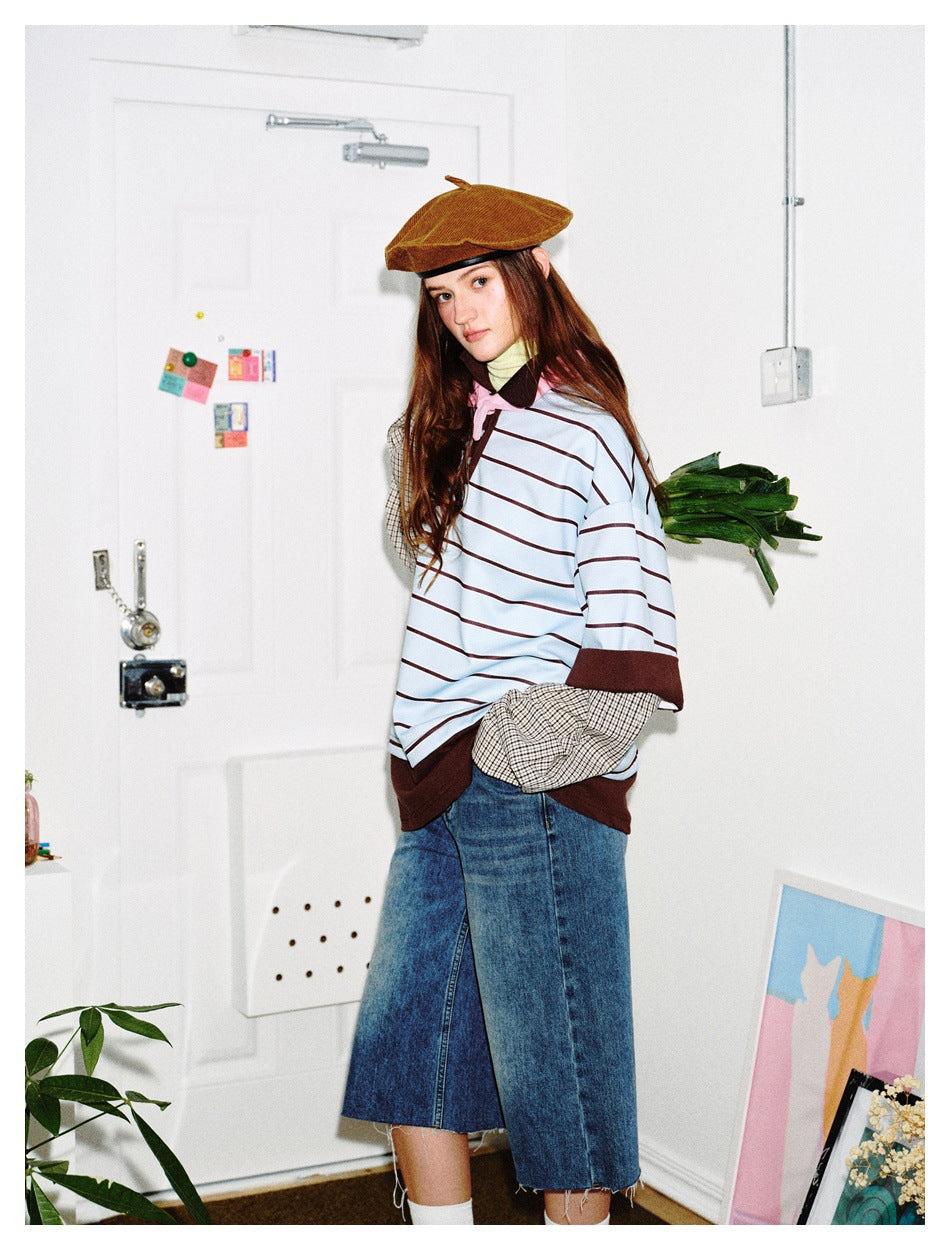 Model wearing the striped layered polo top with checked sleeves and denim skirt, turned slightly to the side