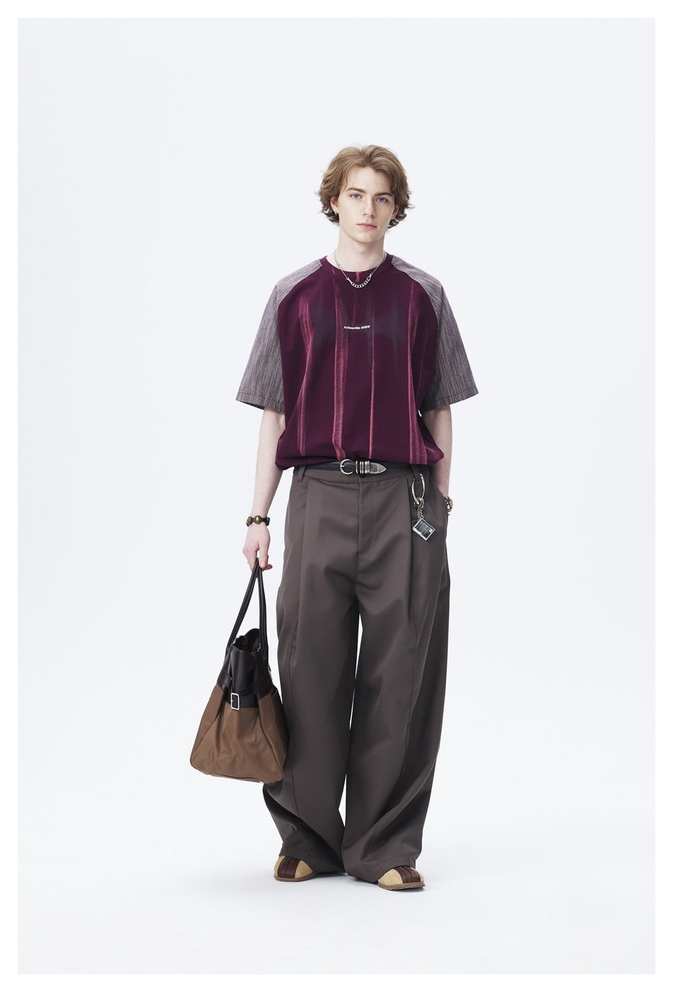 Full-length model wearing a burgundy shirt with gray striped raglan sleeves and wide charcoal trousers.