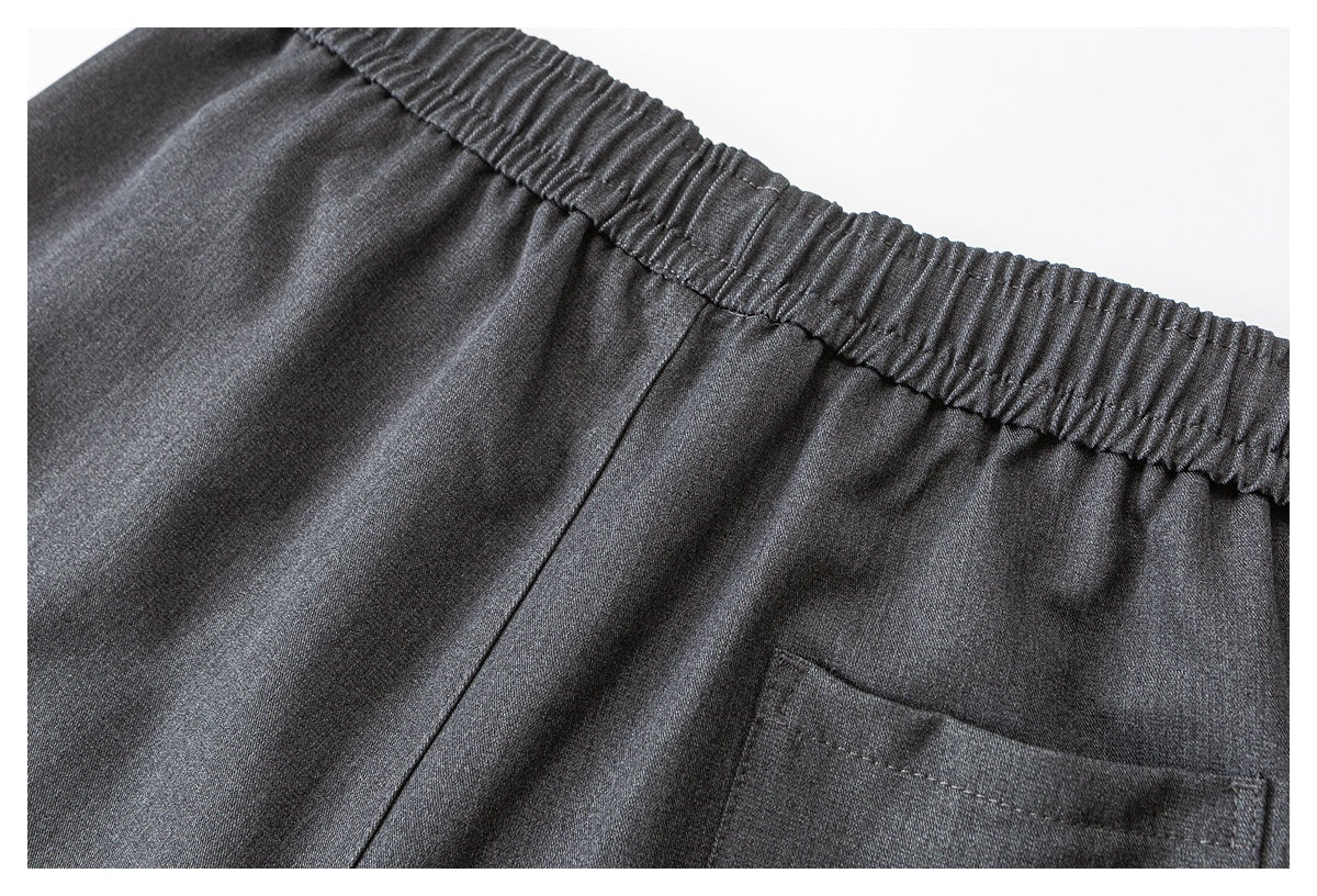 Close-up of the back of charcoal gray pants, showing the elastic waistband and part of a rear pocket.