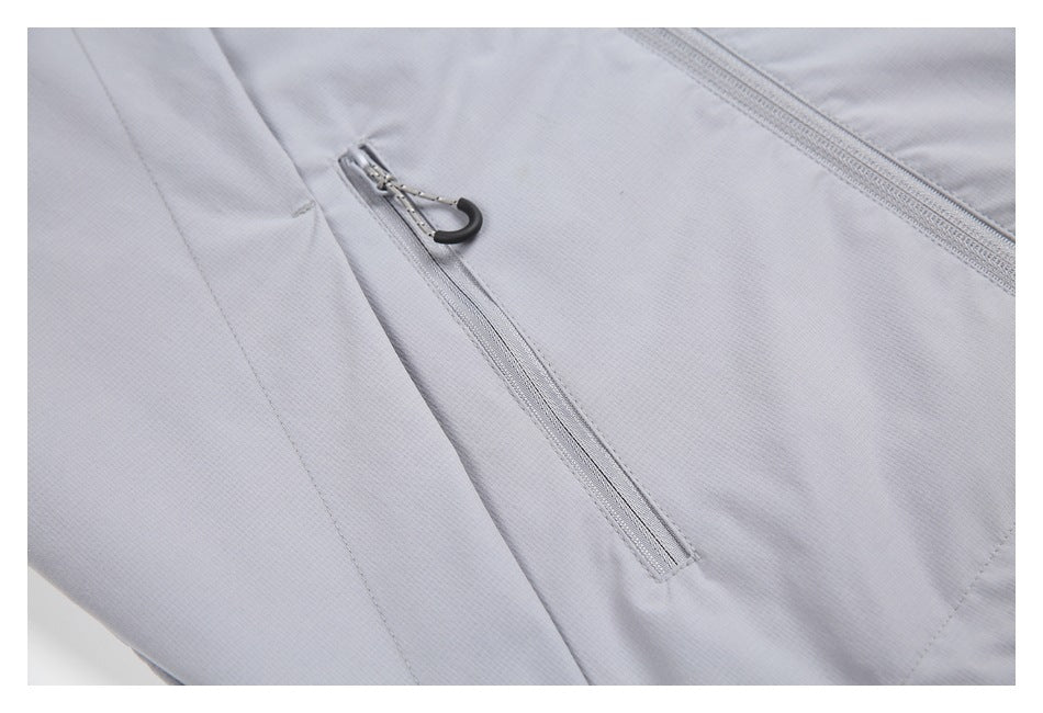 Close-up of a light gray jacket with a slanted zip pocket and black zipper pull.