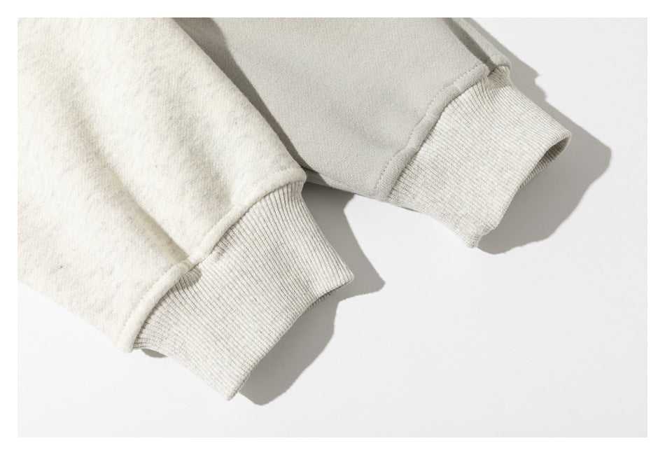 Close-up of two cream sweatshirt sleeves with pale ribbed cuffs against a white background.