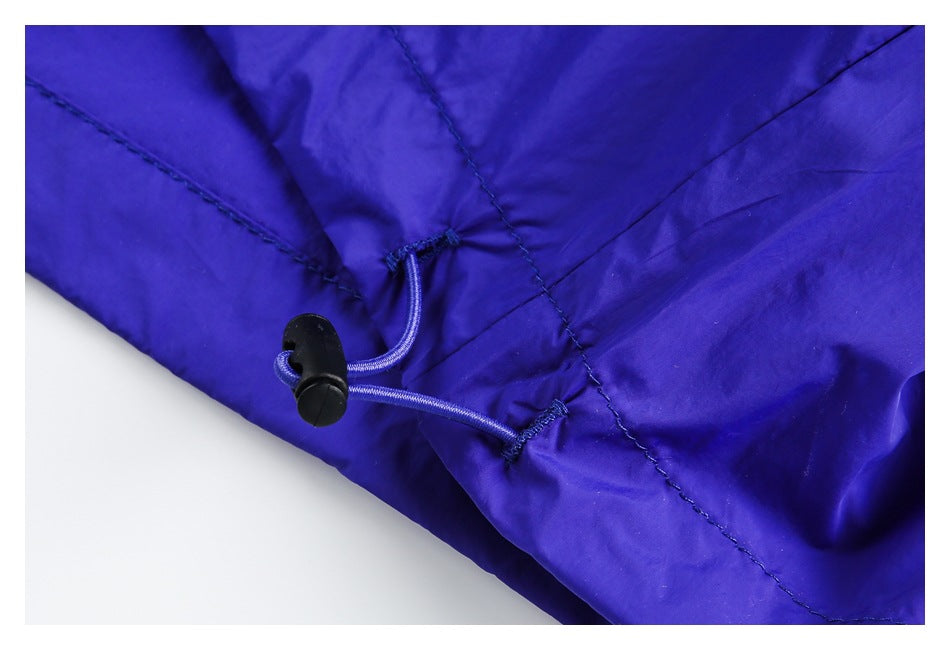 Close-up of a royal blue garment with a cord and black toggle at a stitched seam.