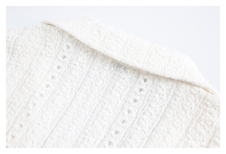 Close-up of the folded collar and eyelet pattern on a white textured garment.