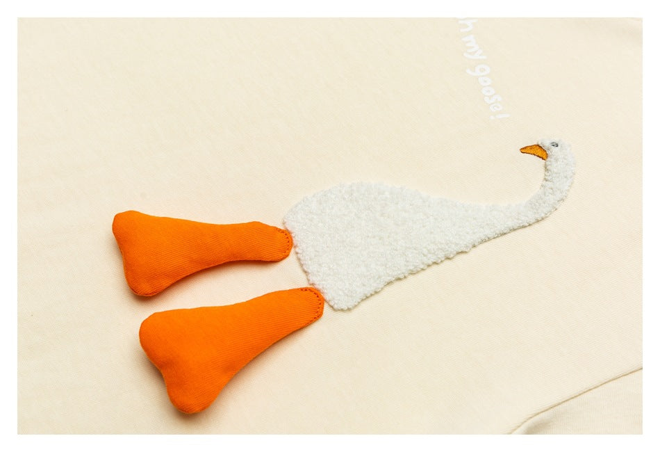 Ivory T-shirt detail with a textured white goose appliqué, orange legs and white lettering.