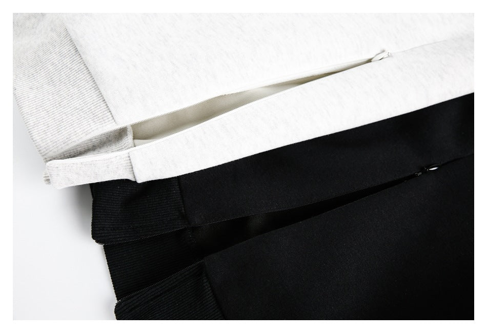 Close-up of light gray and black garments with long zipper openings beside ribbed trim.