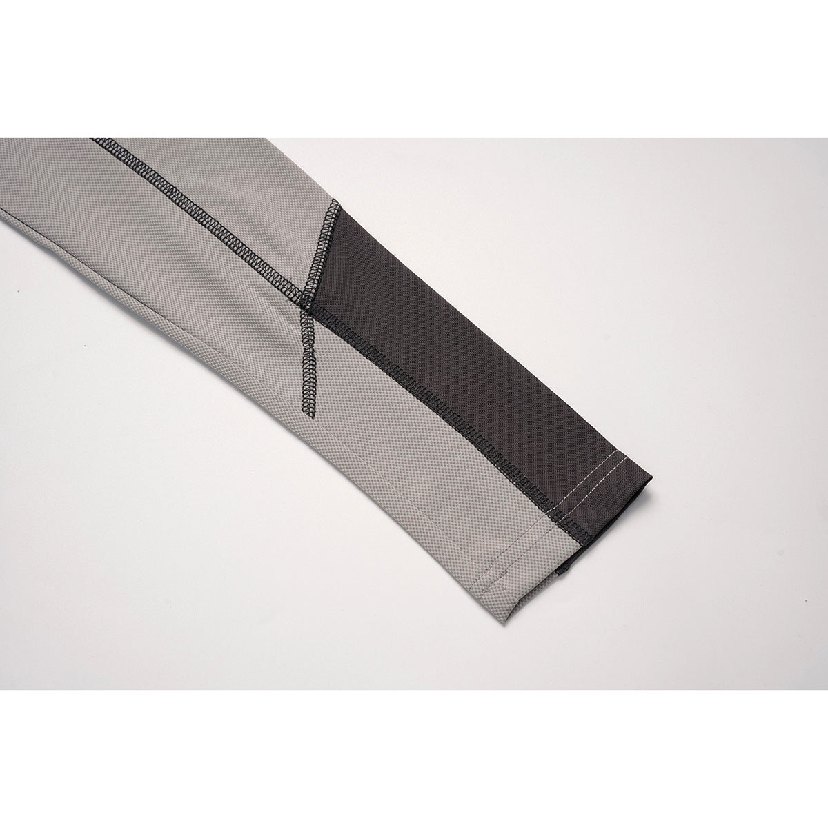 Close-up of the gray top's sleeve cuff with a dark contrast panel and visible stitching.