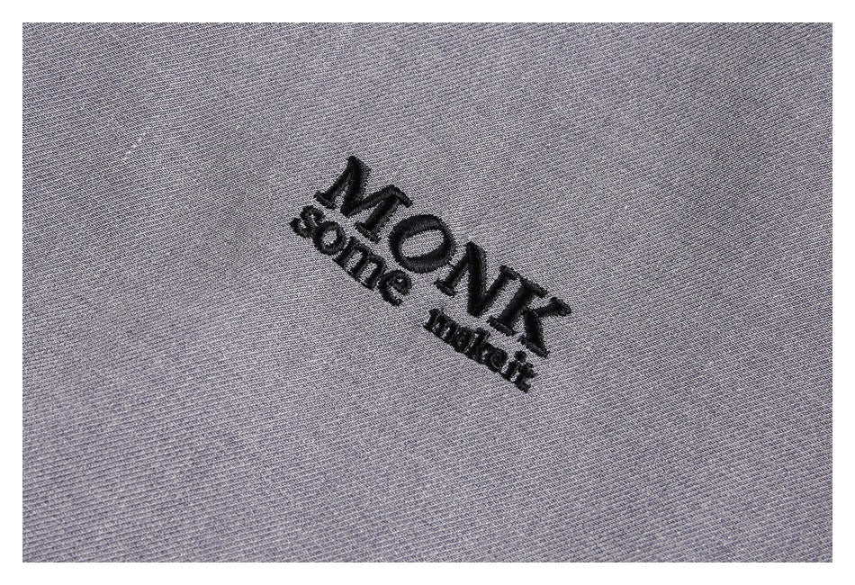 Close-up of black embroidered lettering on gray garment fabric.